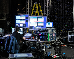 Man in front of numerous computer screens in an audio-video room