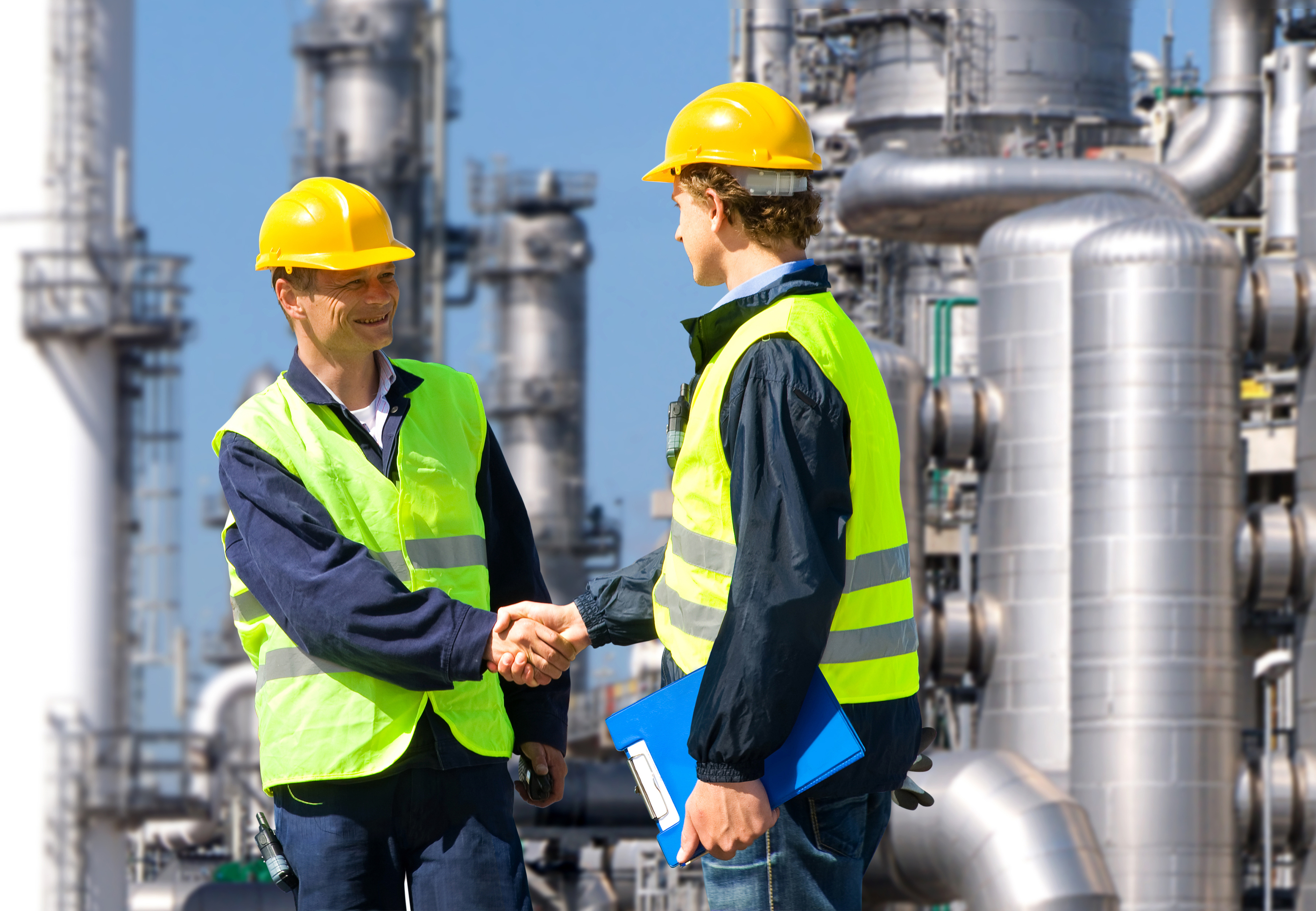 Two petrochemical contractors closing a deal in front of an oil refinary