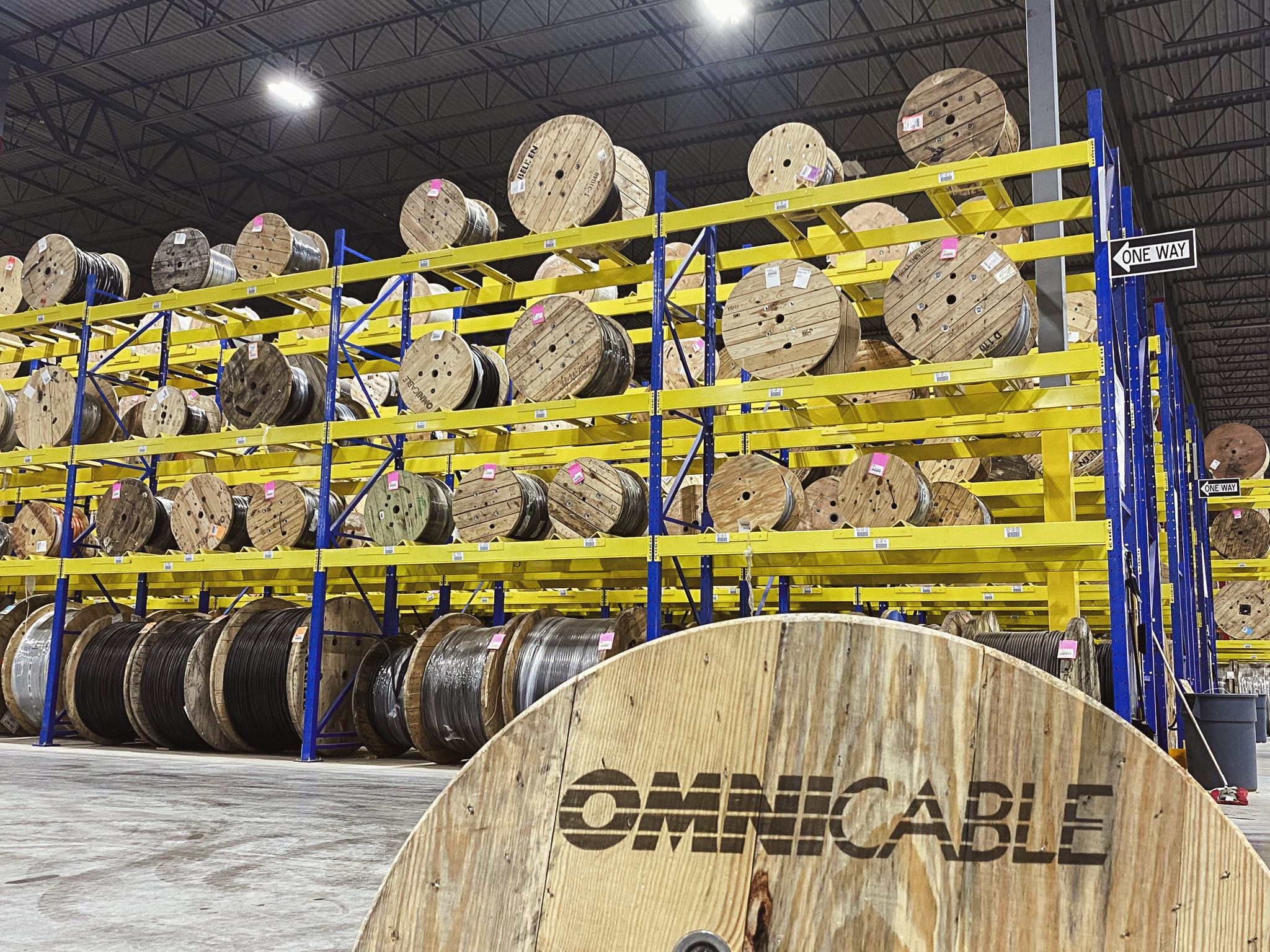 A reel in foreground labeled OmniCable with shelves reels in the background in the warehouse