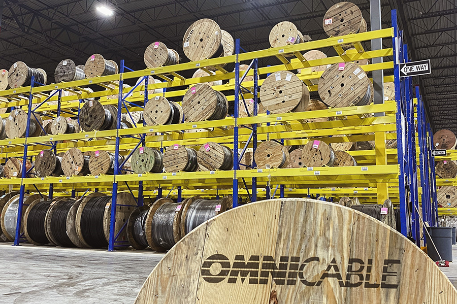 A reel in foreground labeled OmniCable with shelves reels in the background in the warehouse